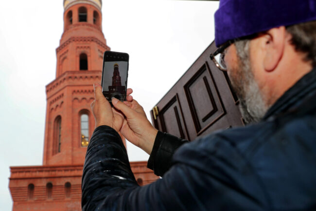священник, мобильный телефон, фотография на смартфон, Исидоровская колокольня Воскресенского Новодевичьего монастыря